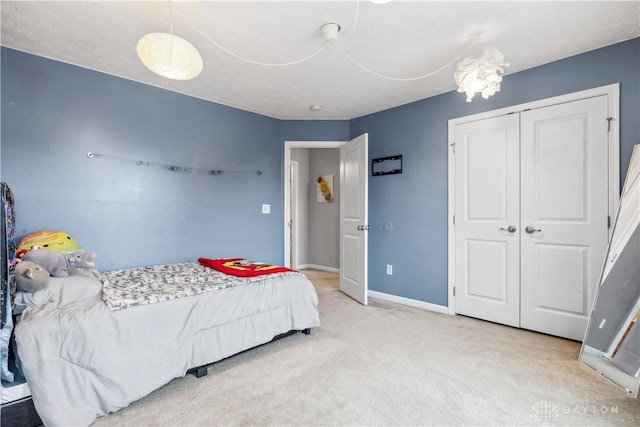 carpeted bedroom with a closet and baseboards