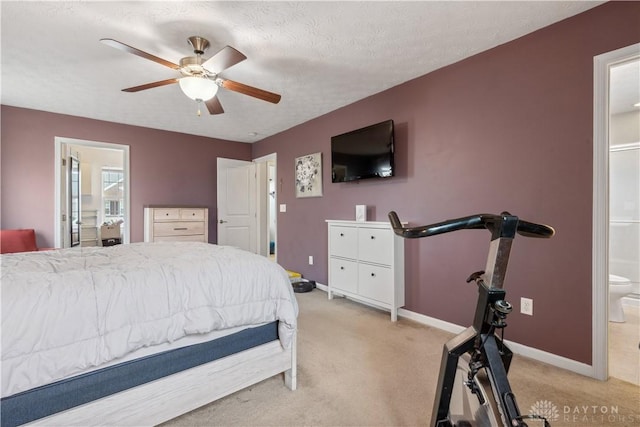 bedroom with a textured ceiling, connected bathroom, light colored carpet, and baseboards