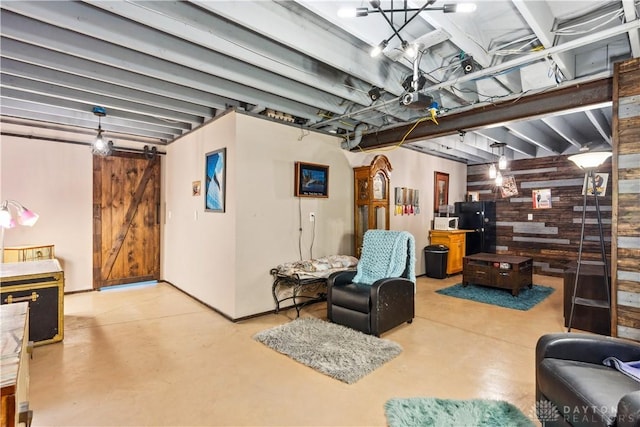 living area featuring finished concrete flooring, wood walls, and a barn door