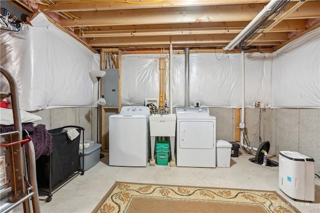 washroom with laundry area, a sink, electric panel, and washer and dryer