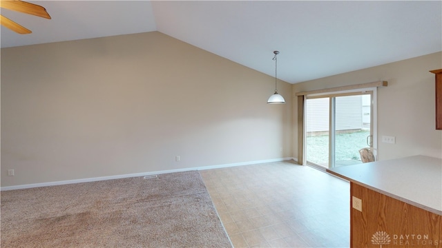 unfurnished dining area with lofted ceiling, light colored carpet, a ceiling fan, and baseboards