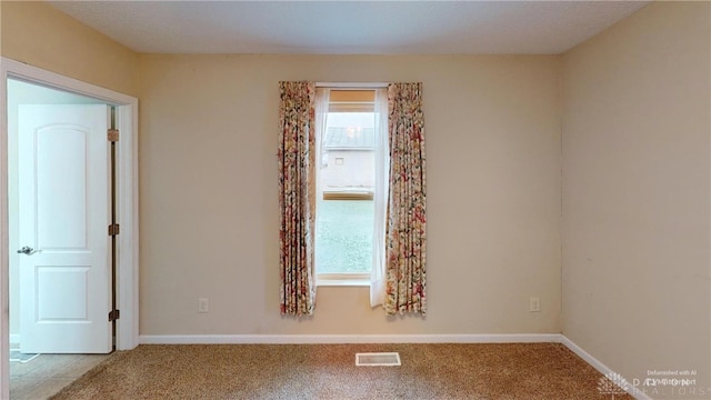 carpeted spare room featuring visible vents and baseboards