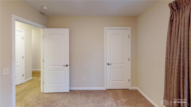 unfurnished bedroom with carpet flooring and baseboards