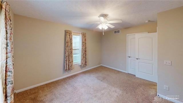 spare room with carpet floors, baseboards, visible vents, and a textured ceiling