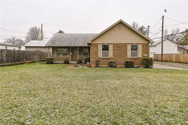 view of front facade with a porch, brick siding, fence, and a front lawn