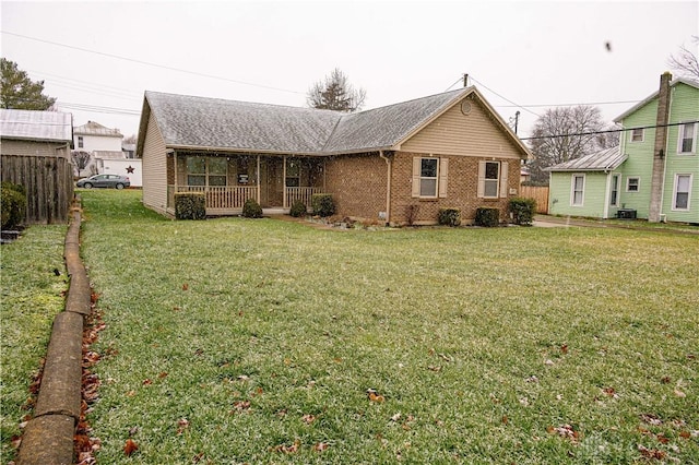 view of front of property with brick siding, roof with shingles, cooling unit, a porch, and a front yard