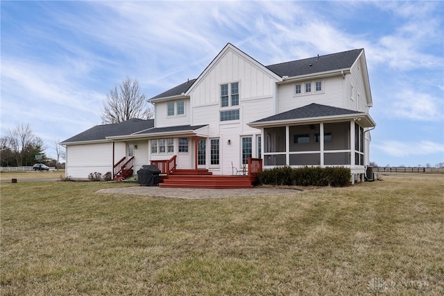 back of property featuring a yard, board and batten siding, and a sunroom