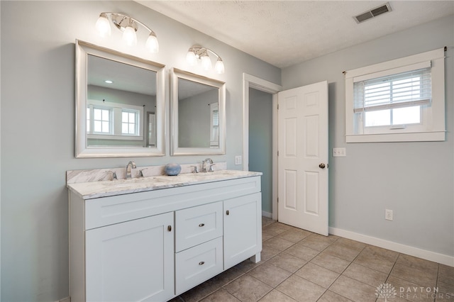 bathroom featuring tile patterned flooring, visible vents, a sink, and double vanity