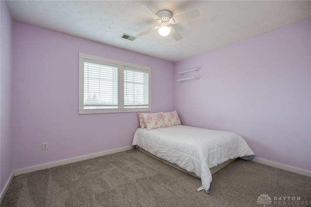 carpeted bedroom with a textured ceiling, ceiling fan, visible vents, and baseboards