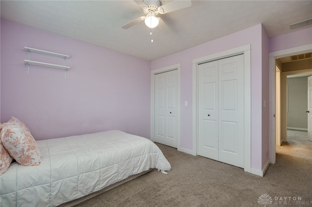 bedroom featuring carpet floors, two closets, visible vents, and baseboards