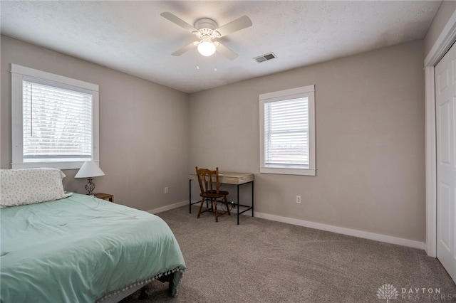 carpeted bedroom with ceiling fan, a textured ceiling, visible vents, and baseboards