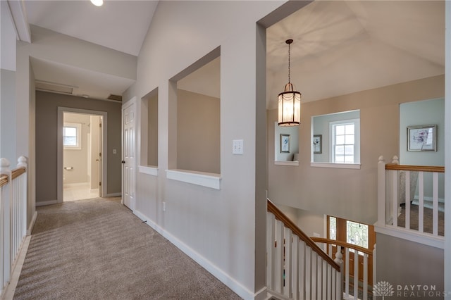 corridor featuring lofted ceiling, baseboards, carpet flooring, and an upstairs landing