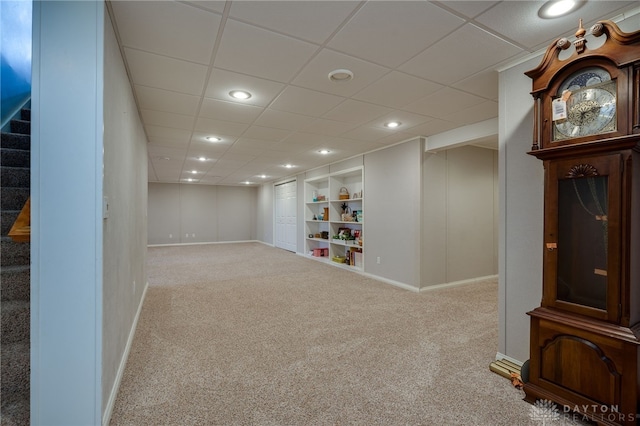 finished below grade area with built in shelves, recessed lighting, carpet floors, baseboards, and stairway