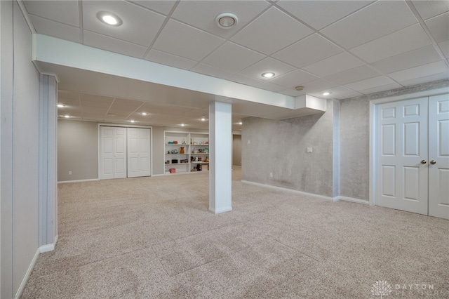 finished basement with a drop ceiling, recessed lighting, carpet floors, baseboards, and built in features