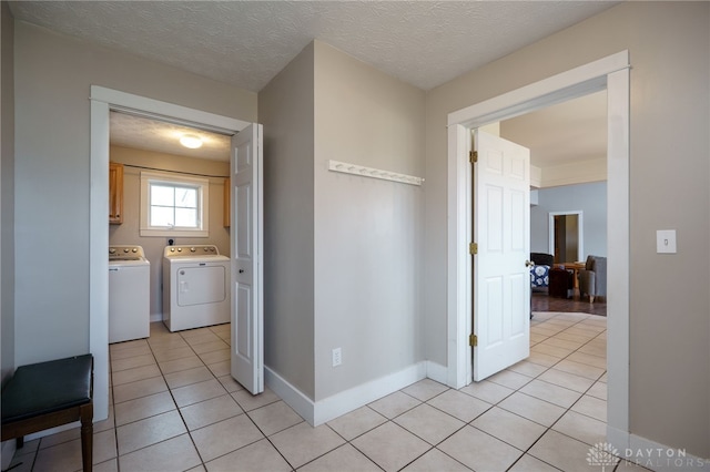 hall featuring independent washer and dryer, a textured ceiling, baseboards, and light tile patterned floors