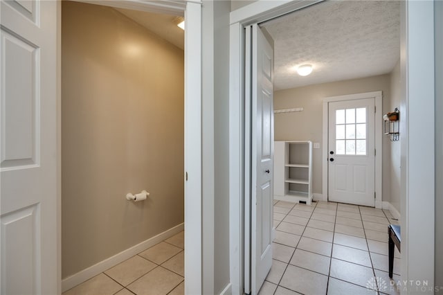 interior space featuring baseboards, a textured ceiling, and light tile patterned flooring