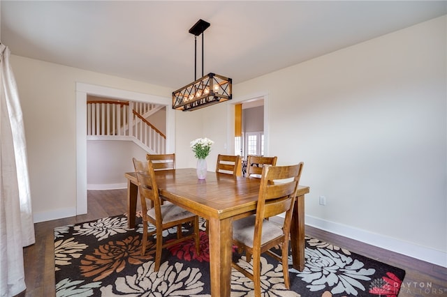 dining space with stairway, a notable chandelier, baseboards, and wood finished floors