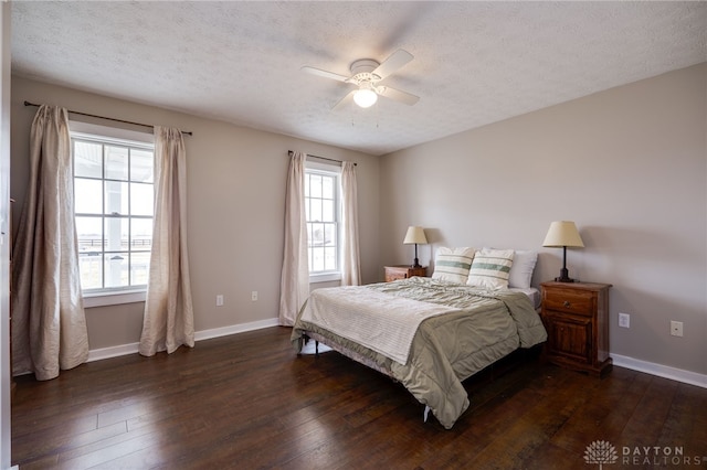 bedroom with ceiling fan, baseboards, dark wood finished floors, and a textured ceiling