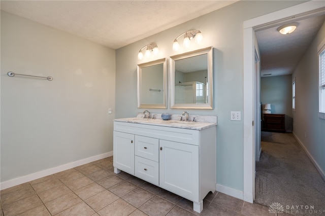 full bathroom with double vanity, baseboards, and a sink