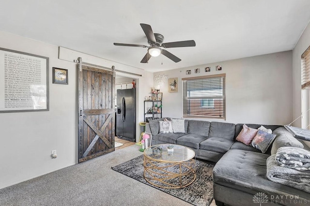 living room with a barn door, a ceiling fan, and light colored carpet