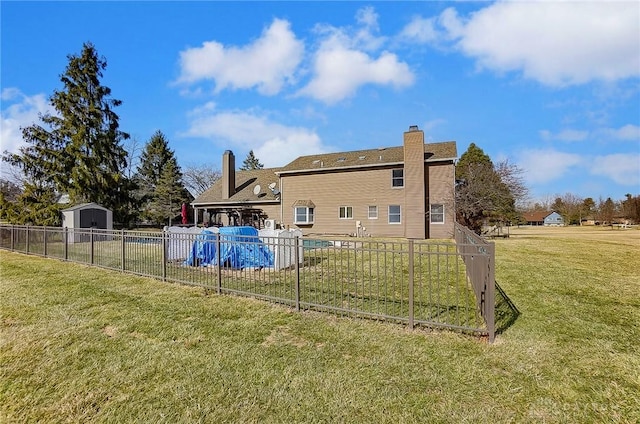 rear view of house with a shed, fence, an outbuilding, and a yard