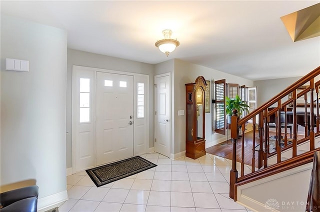 entrance foyer with light tile patterned floors, baseboards, and stairway