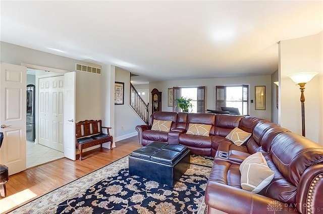 living area featuring baseboards, stairs, visible vents, and wood finished floors