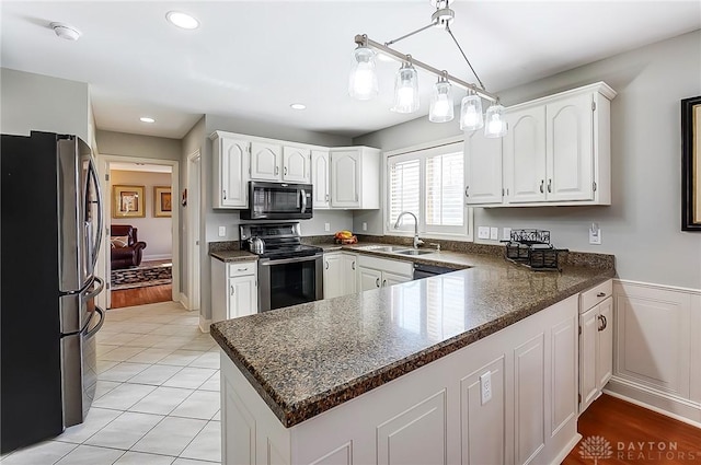 kitchen featuring recessed lighting, stainless steel appliances, a peninsula, a sink, and white cabinetry