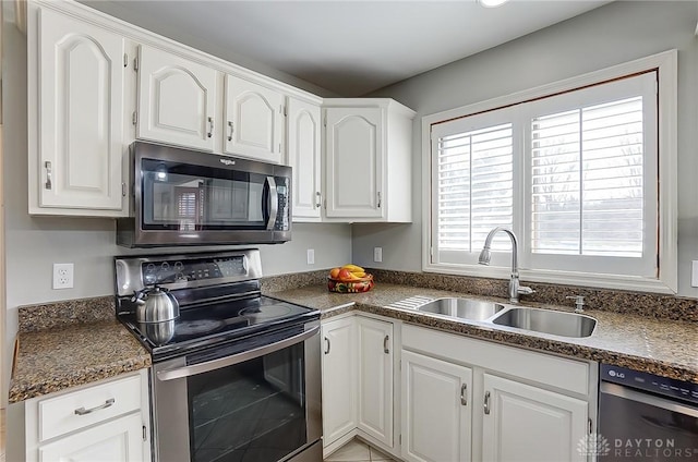 kitchen with appliances with stainless steel finishes, dark countertops, white cabinetry, and a sink