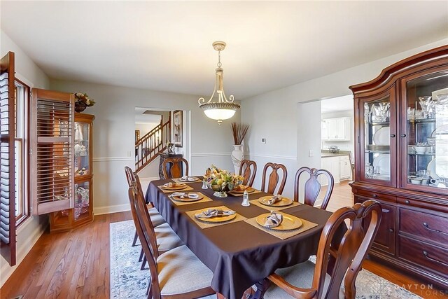 dining room with stairway, light wood-style flooring, and baseboards