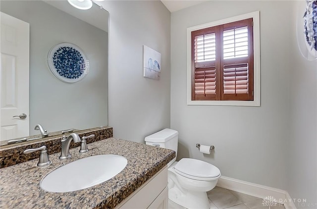 half bath with vanity, tile patterned floors, toilet, and baseboards