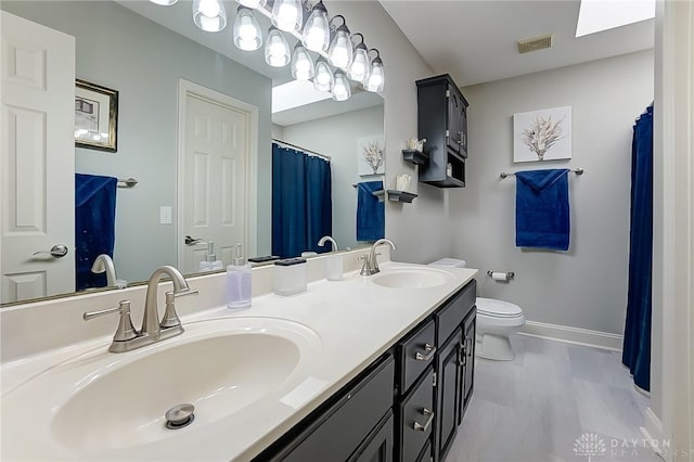 bathroom featuring toilet, a sink, visible vents, and baseboards