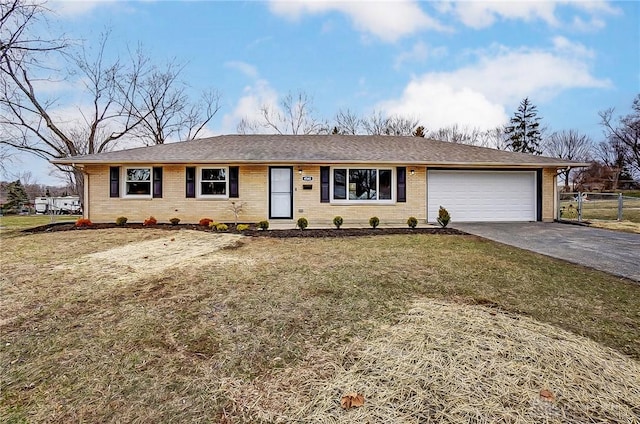 single story home featuring a front yard, fence, a garage, aphalt driveway, and brick siding