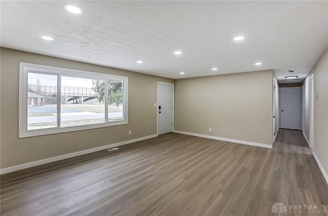 empty room featuring recessed lighting, wood finished floors, and baseboards