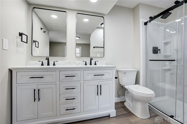 full bathroom featuring a sink, toilet, wood finished floors, and a shower stall