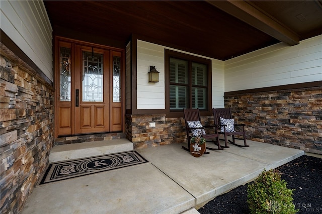 entrance to property with stone siding and a porch