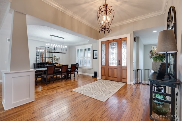 entrance foyer featuring a chandelier, light wood finished floors, and crown molding