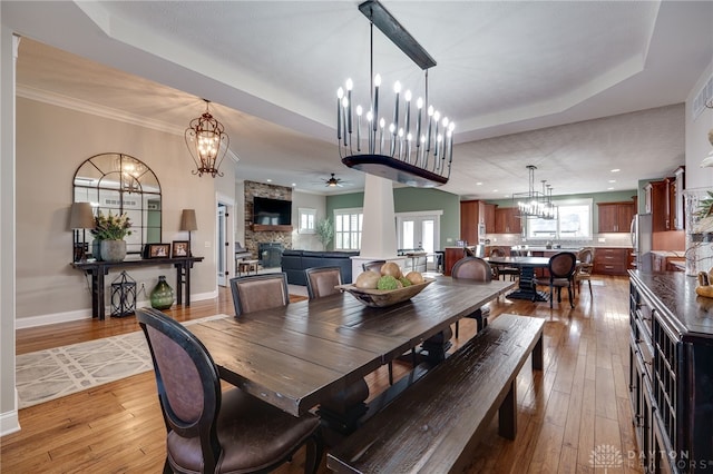 dining area featuring crown molding, recessed lighting, wood-type flooring, a stone fireplace, and baseboards