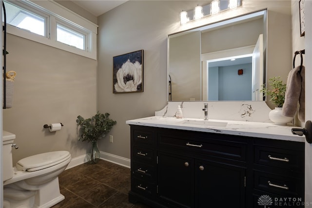 bathroom with toilet, baseboards, and vanity