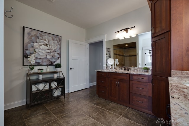 bathroom with tiled shower, vanity, and baseboards