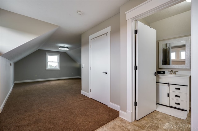 additional living space with light colored carpet, vaulted ceiling, and baseboards