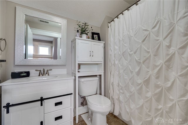 bathroom with a textured ceiling, visible vents, vanity, and toilet