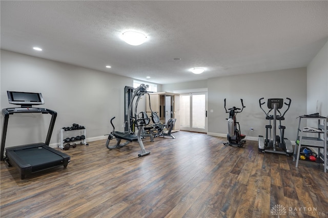 workout area featuring a textured ceiling, baseboards, and wood finished floors