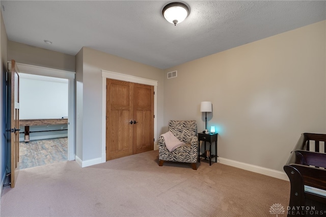 living area featuring carpet, visible vents, a textured ceiling, and baseboards