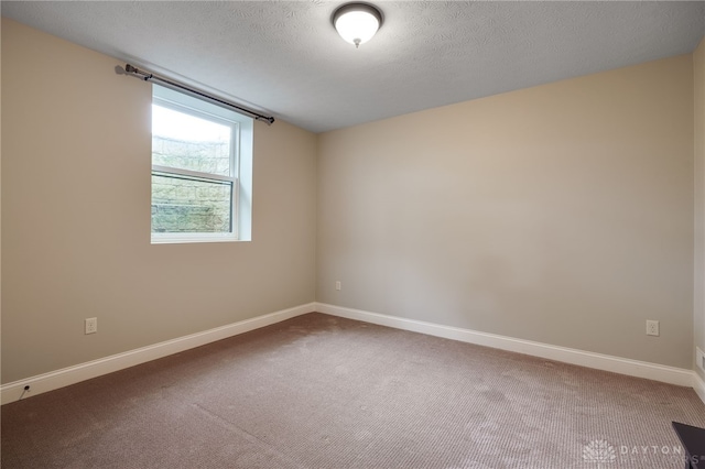 carpeted empty room featuring baseboards and a textured ceiling