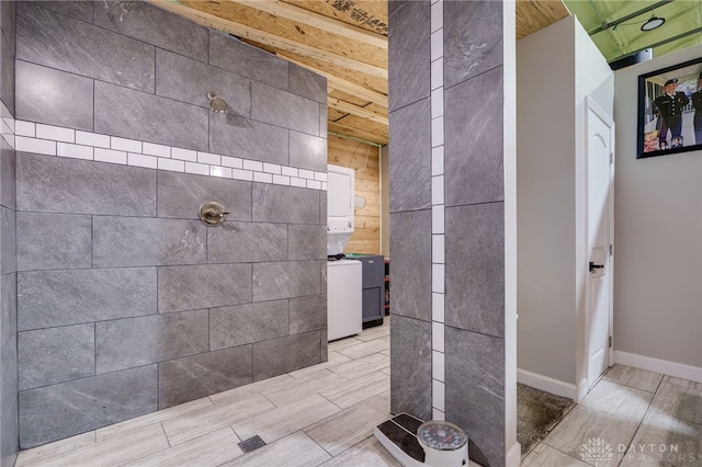 bathroom featuring stacked washer and dryer and tiled shower