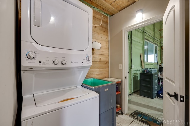 laundry room featuring stacked washer and dryer, wood walls, and laundry area