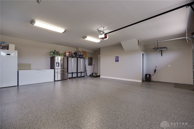 garage featuring fridge, stainless steel fridge, and a garage door opener