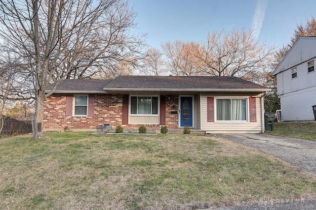 ranch-style house with driveway, a front yard, fence, and brick siding