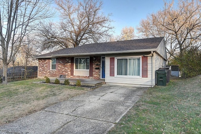 view of front of home with roof with shingles, brick siding, and a front lawn